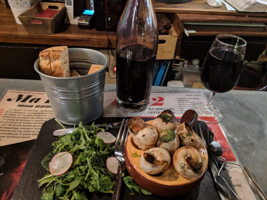escargot with a arugula salad, bread, and wine in Paris France